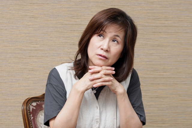 椅子に座り行動できない理由を考えているシニア女性