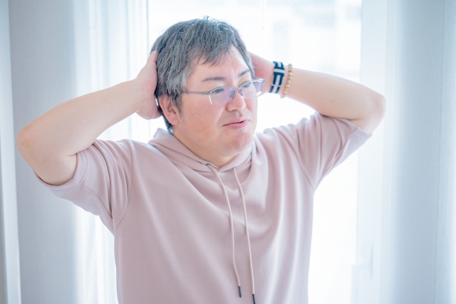 頭を抱えて考えているシニアの男性