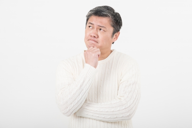 手をあごにやり、考えをめぐらすシニアの男性